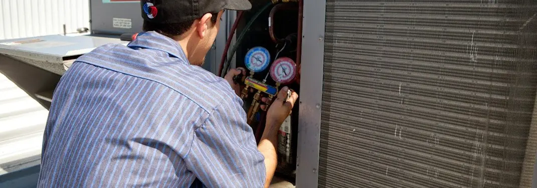 HVAC technician servicing a condenser unit in Woodbury